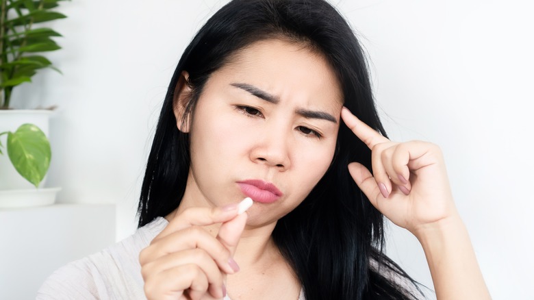 confused woman holding pill