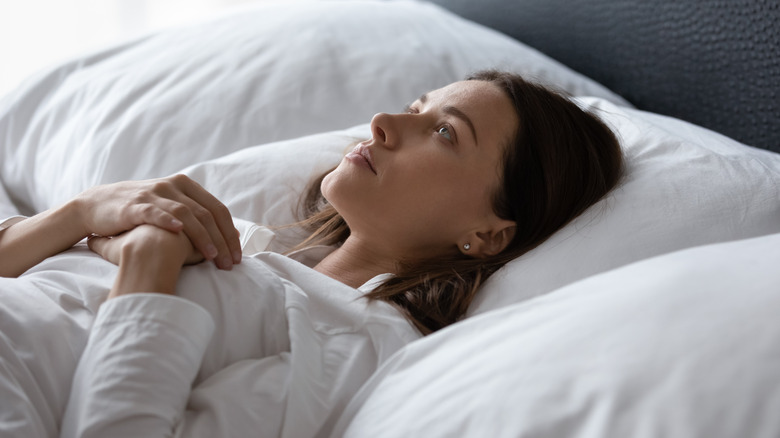 Side view of a woman lying in bed wide awake 