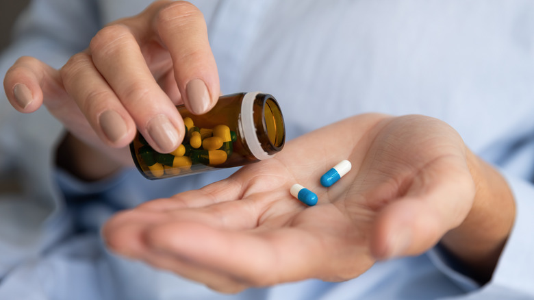 Person pouring capsules out of bottle