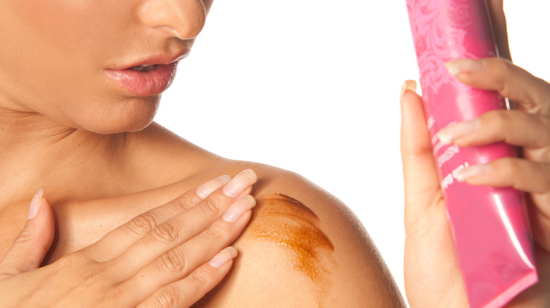 woman applying fake tanner to her shoulder 