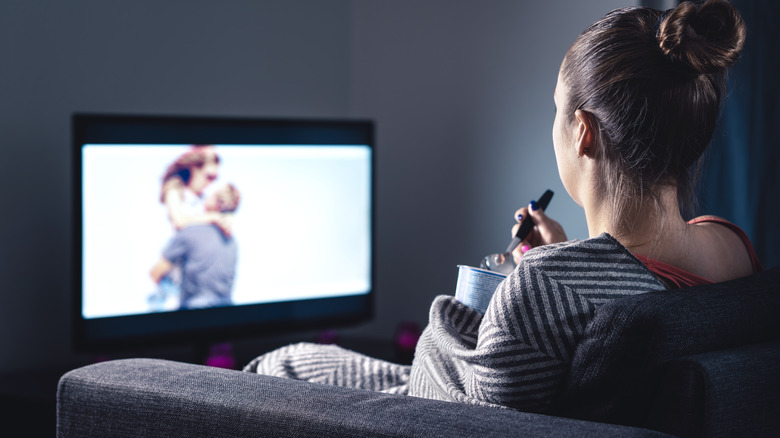 woman watching tv eating unhealthy snacks