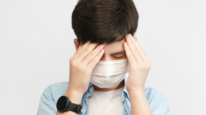 Kid touching forehead with mask on