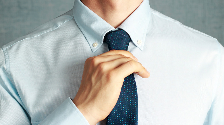 Close-up of hand adjusting necktie