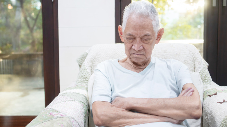 Elderly man asleep upright in chair