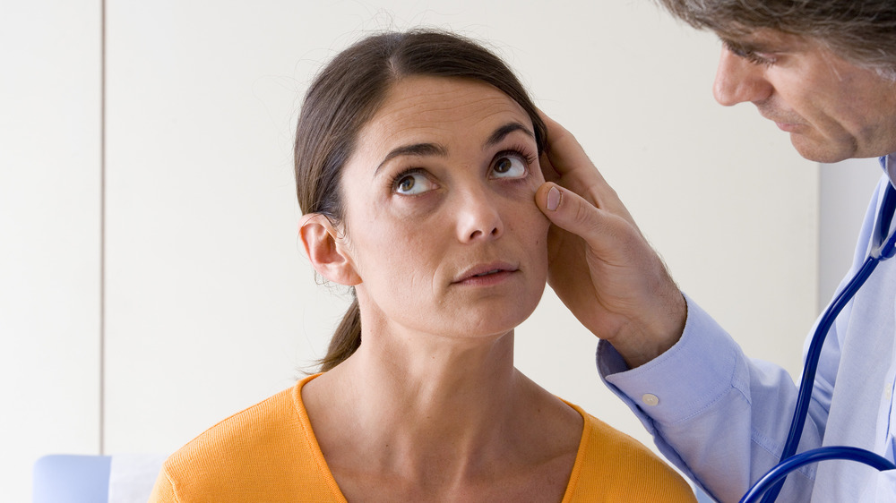 doctor examining woman's eyelid for signs of anemia
