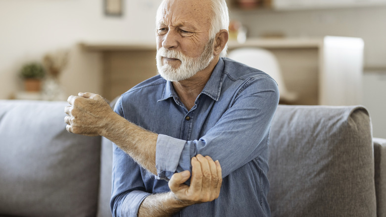 Older man holding elbow