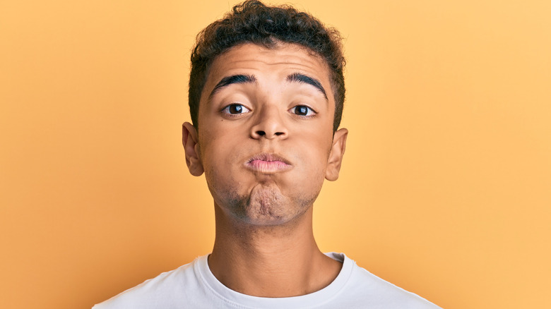 Young man holding his breath with puffy cheeks