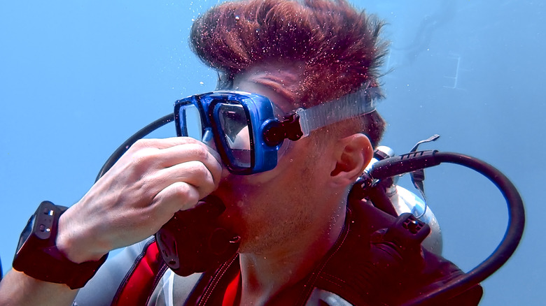 Underwater diver holding nose and wearing an oxygen mask