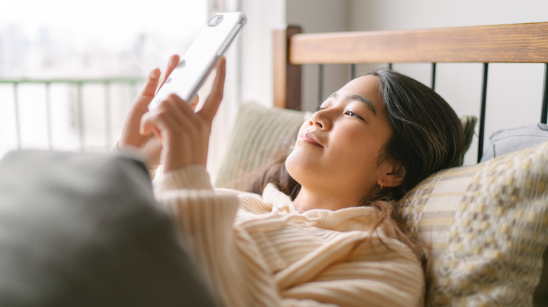Woman looking at phone in bed