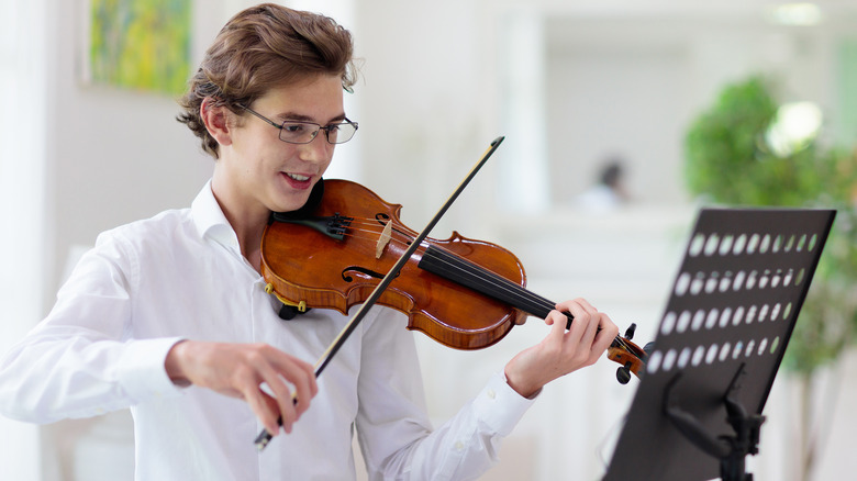 Young man playing the violin while reading music 