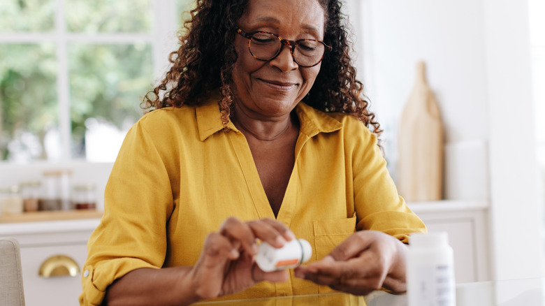 A woman dispensing a pill onto her hand