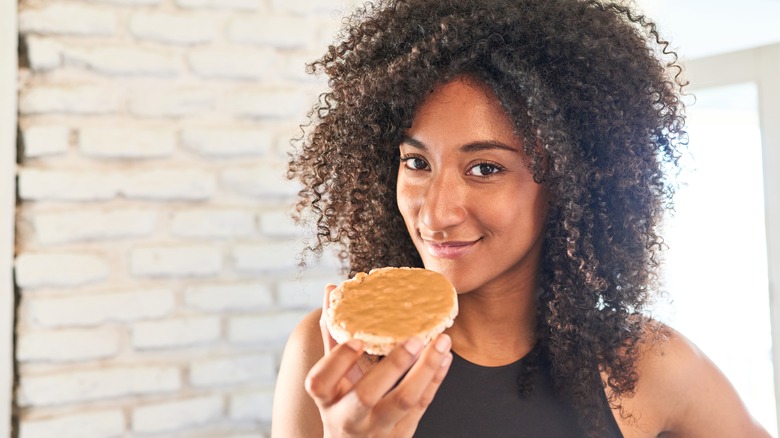 woman eating peanut butter on a rice cake