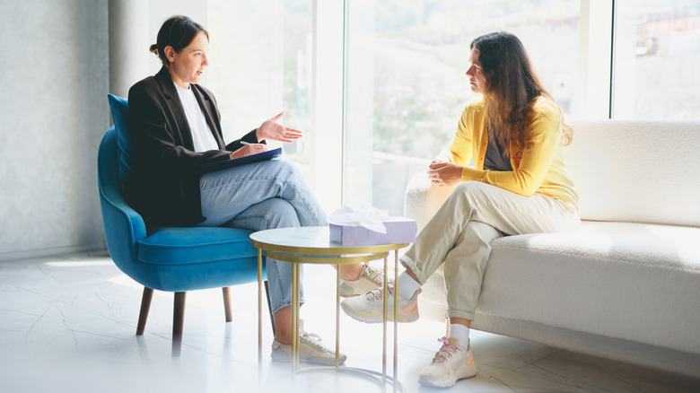 A woman talking with her therapist in a room with a large window