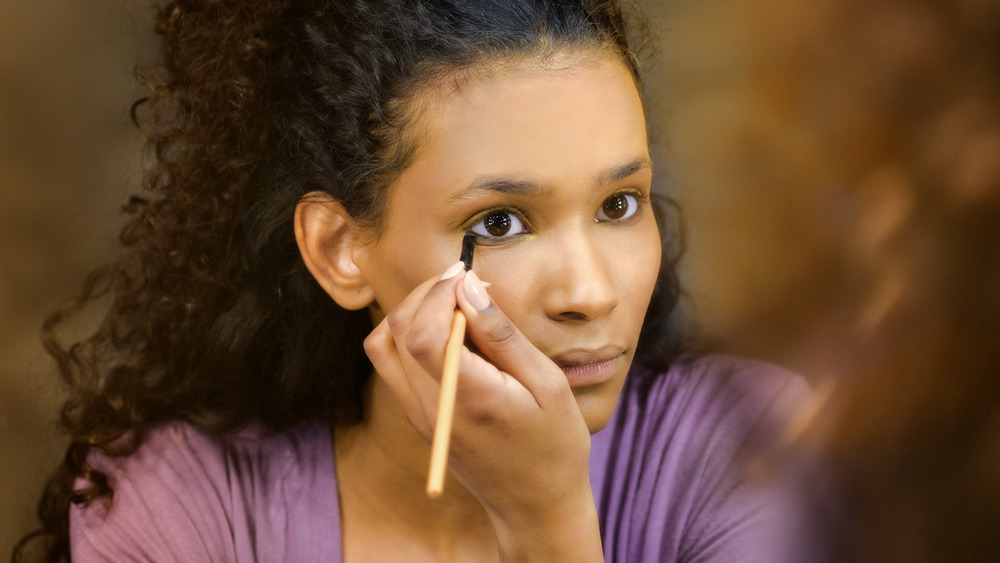 woman applying makeup in mirror