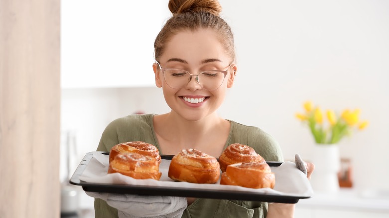 woman holding tray of fresh cinnamon rolls