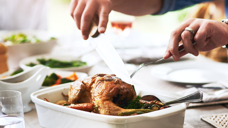 Hands slicing roast chicken