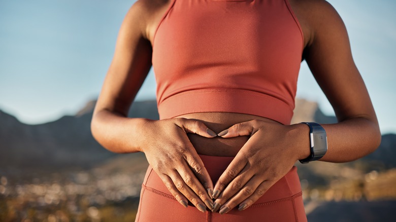 fit woman holding hands over gut area