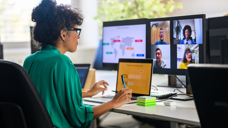 A woman working productively from home in front of several monitors and computers