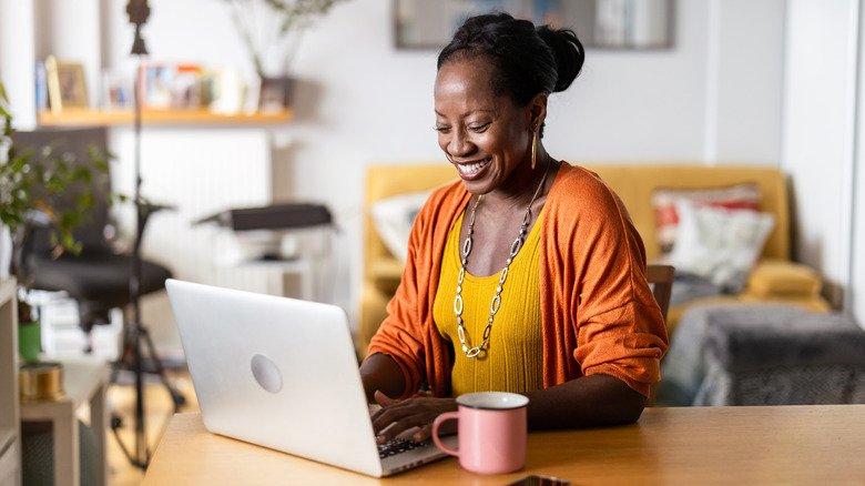 A smiling woman working from home on her laptop