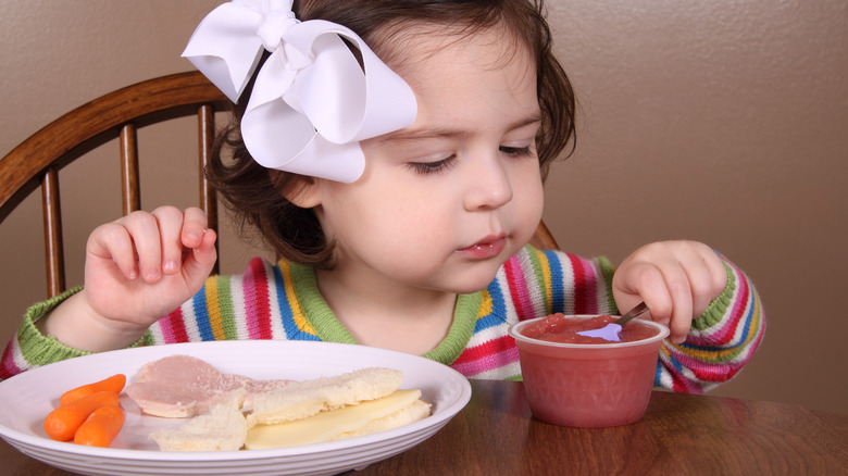 little girl eating applesauce as a side dish
