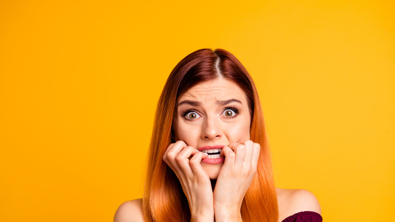 Young scared woman on yellow background