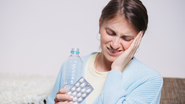 woman with toothache holding ibuprofen