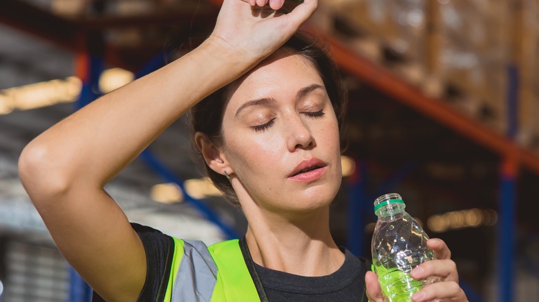 tired female worker holding bottled water