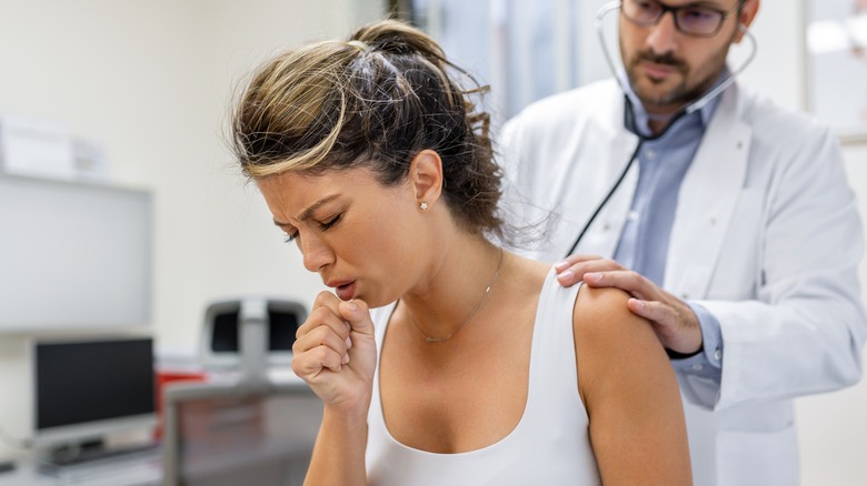 doctor listening to coughing patient's lungs