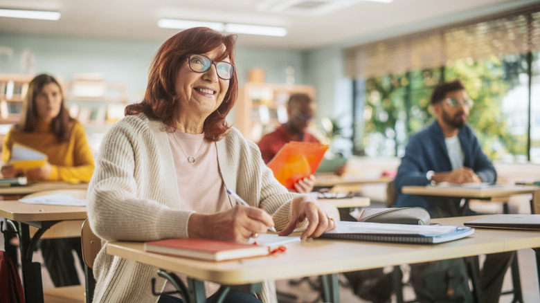 older woman taking notes in a classroom