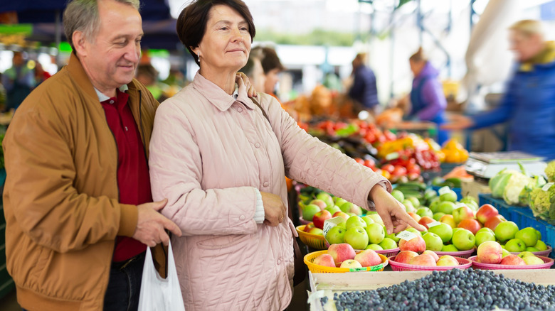 older man and woman buying blueberries at market
