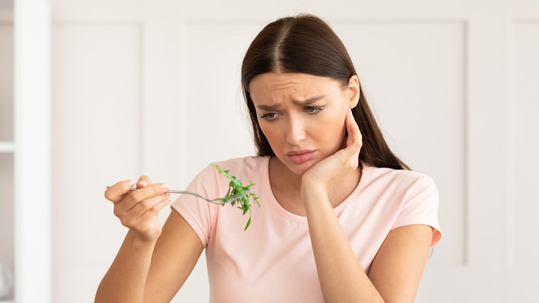 woman unhappy with a fork of greens