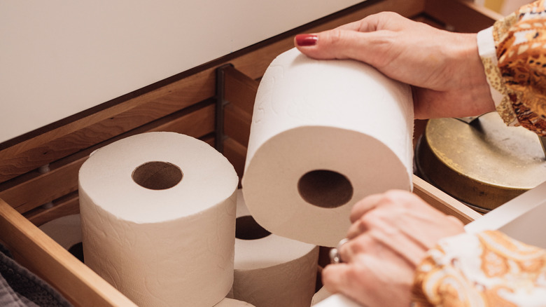 woman reaching for another roll of toilet paper