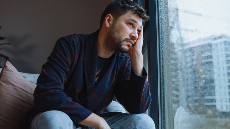 man looking lonely as he sits on sofa