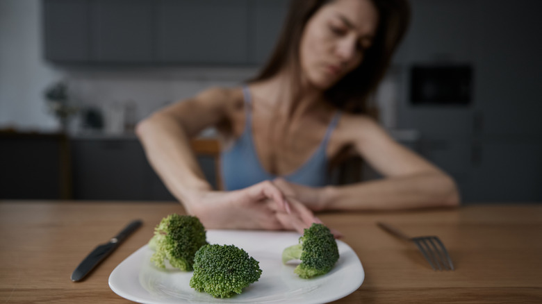 woman pushing away plate of broccoli