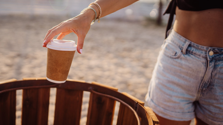 Hand throwing away coffee cup