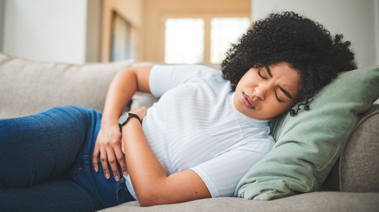 person holding stomach on couch