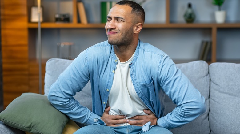 man sitting on the couch with abdominal pain