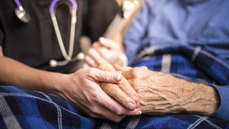 Nurse holding hands of senior patient