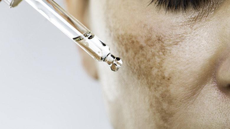 Medicine dropper on skin's dark spots