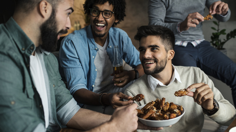 Male friends eating plate of chicken