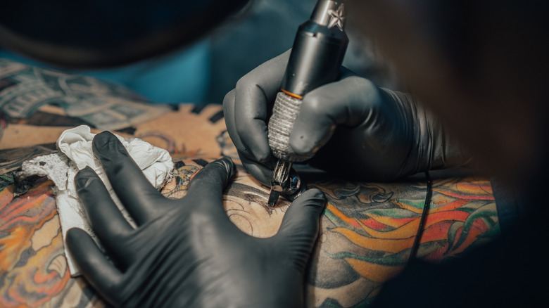 Gloved hands giving someone a tattoo