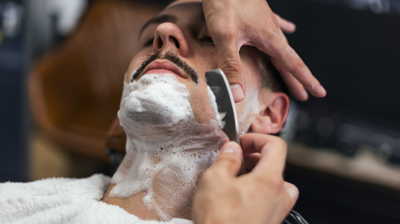 Man being shaven by a barber
