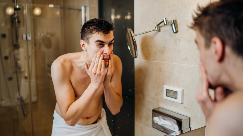 Man applying aftershave to face