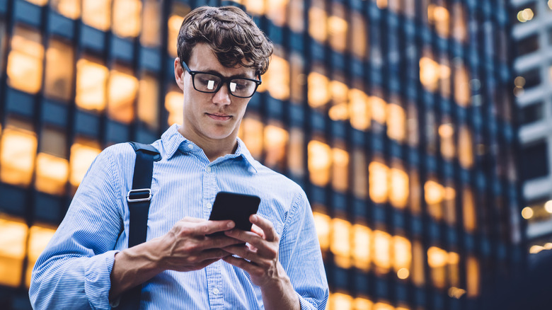 man in glasses texting on a phone