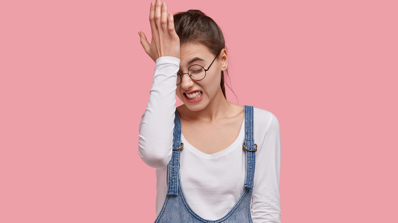 Woman forgetting in front of pink background