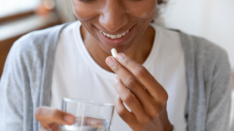 A young woman is taking a probiotic supplement