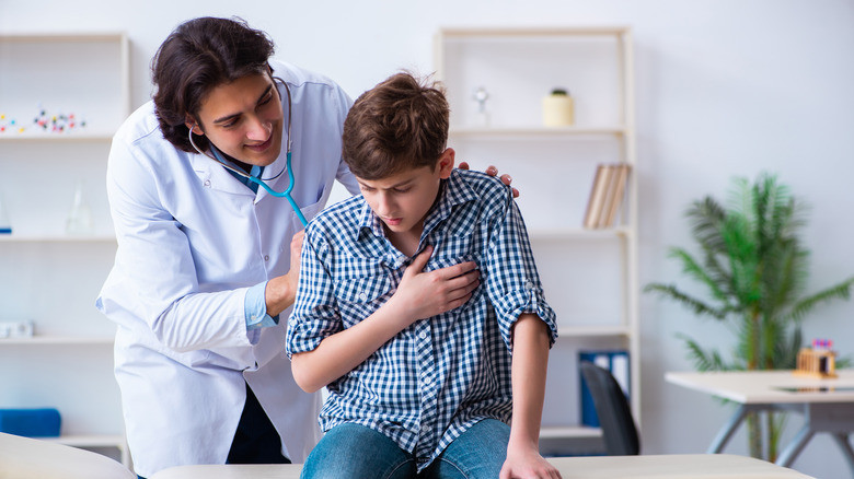 A doctor is examining a boy with lung problems
