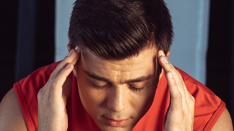 young man looking hungover in fitness wear 