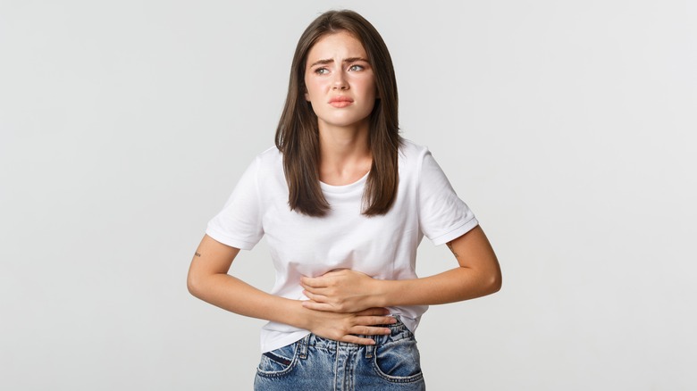 a young woman holds her stomach in discomfort