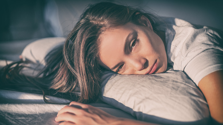 A woman laying in bed looking uncomfortable